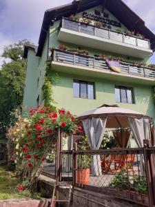 a building with an umbrella and flowers in front of it at Pensiunea Ana in Cavnic