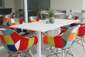 una mesa blanca con sillas coloridas en una habitación en Esperidi Paestum Agri Resort, en Capaccio-Paestum