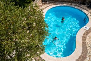 two people swimming in a pool with blue water at Apartments Villa Klaudia - Adults Only in Crikvenica