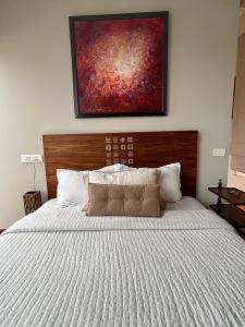 a bedroom with a large bed with a painting on the wall at Green Cottage Oriental in Panchkula