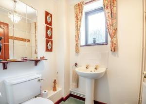 a bathroom with a sink and a toilet and a window at Woodlands in Newent