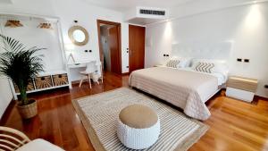 ein Schlafzimmer mit einem großen weißen Bett und einem Tisch in der Unterkunft Hotel & Wellness Fra I Pini in Lignano Sabbiadoro