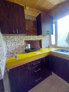a kitchen with a yellow counter top and a window at The Shudarang Inn in Kalpa