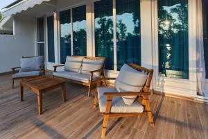 two chairs and a table on a porch with windows at River Breeze House in Sremska Kamenica
