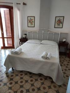 ein Schlafzimmer mit einem weißen Bett mit zwei Handtüchern darauf in der Unterkunft Arenella Beach Rooms in Arenella