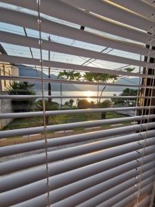 a window with a view of the beach through the blinds at Trinity Apartment Seafront in Kotor