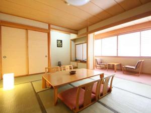 Habitación con mesa de madera, sillas y ventanas. en ぽかぽかランド美麻, en Omachi