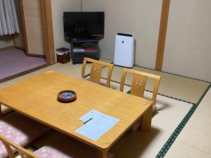 una mesa de madera y sillas en la sala de estar. en ぽかぽかランド美麻, en Omachi