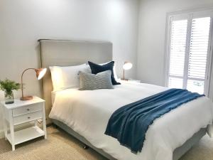 a bedroom with a large white bed with blue sheets and pillows at Seppeltsfield Vineyard Retreat - 3 Bedroom Holiday Home in Seppeltsfield