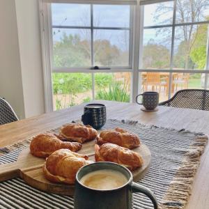 a wooden table with croissants and a cup of coffee at Seppeltsfield Vineyard Retreat - 3 Bedroom Holiday Home in Seppeltsfield