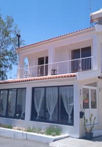 a white house with windows and a balcony at Jonty Villa, Mazotos in Larnaka