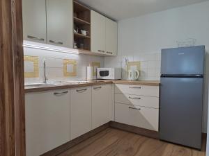 a kitchen with white cabinets and a refrigerator at Apartments Pr'Krštano in Kranjska Gora
