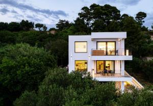 una casa blanca en una colina con árboles en Panorama Suite Dora with Jacuzzi, en Palit