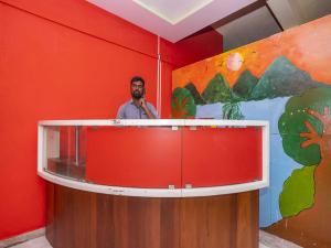Un uomo in piedi dietro un podio in una stanza rossa di OYO Flagship 28067 Shree Stays a Bangalore