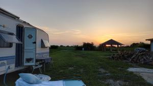 uma caravana estacionada num campo com o pôr-do-sol ao fundo em Cazare in rulota, zona pentru gratar si relaxare, jacuzzi se inchiriaza la un cost suplimentar de 250 lei pe zi em Prejmer