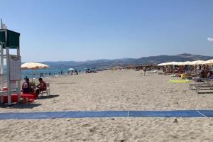 un grupo de personas sentadas en una playa con sombrillas en Appartement idéal pour découvrir le Sud d'Italie, en Nova Siri Marina