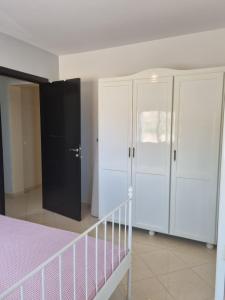 a bedroom with white cabinets and a pink bed at Appartement Al hoceima in Al Hoceïma