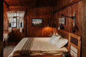 1 dormitorio con 1 cama en una pared de madera en Cloud Forest Tà Xùa, en Bắc Yên