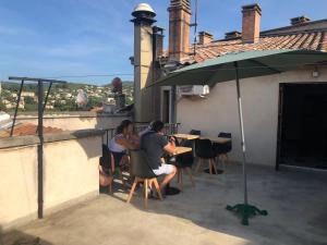 Un groupe de personnes assises à une table sous un parapluie dans l'établissement Hotel François 1Er, à Manosque