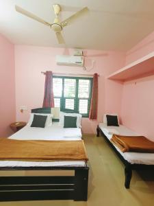 Duas camas num quarto com paredes cor-de-rosa em Maanyatha Home Stay em Manipal