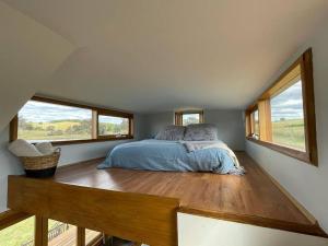 a bedroom with a bed in a room with windows at 'Bertie' Tiny House on a Lake in a Vineyard in Hall