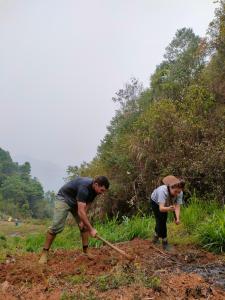due persone che lavorano in un campo con una pala di Indigenous homestay 1- Trek- Vegetarian- Bus a Mù Cang Chải