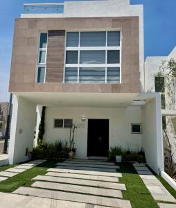 uma grande casa branca com uma porta preta em Acogedora y amplia casa, alberca climatizada previa reserva em Juriquilla