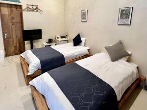 a bedroom with two beds and a television in it at Enfield一宮 in Ichinomiya