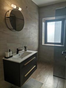 een badkamer met een wastafel, een spiegel en een raam bij Studio Luna in Bale
