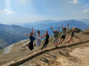 um grupo de pessoas a saltar no topo de uma colina em Indigenous homestay- Trek- Food- Bus em Mù Cang Chải