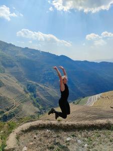 una mujer saltando en el aire en la cima de una montaña en Indigenous homestay 1- Trek- Vegetarian- Bus en Mù Cang Chải