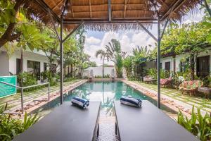 a swimming pool with two benches in front of a house at The Botanic Garden Hotel in Siem Reap