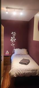 um quarto com uma cama com uma parede roxa em NALA HOUSE, acogedor,bien comunicado,aparcamiento gratis en la calle em Bilbao