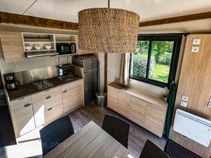 a kitchen and dining room of a caravan at Camping Onlycamp Le Pont Romain in Yvré-lʼÉvêque