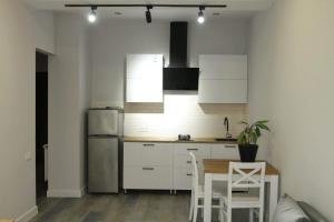 Апартаменты на Сабуртало في تبليسي: مطبخ بدولاب بيضاء وطاولة وثلاجة
