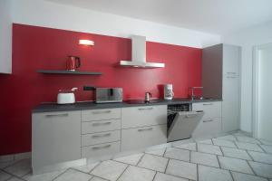 a kitchen with white cabinets and red walls at Casa Carla in Nago-Torbole