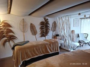 a bedroom with two beds and palm trees on the wall at Mas de l'Amme in Valréas