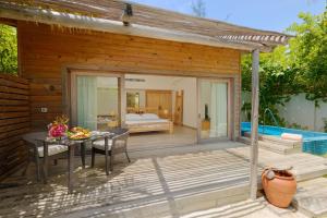 a patio with a table and a bed and a bedroom at You & Me Maldives - Adults Only - Premium All-Inclusive in Raa Atoll