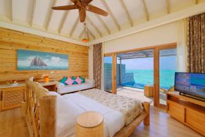 a bedroom with a bed and a tv and a balcony at You & Me Maldives - Adults Only - Premium All-Inclusive in Raa Atoll