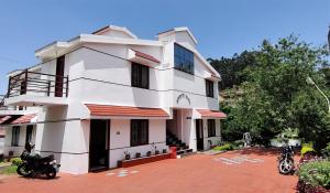 a white building with motorcycles parked in front of it at Ganapathy Garden Homestay in Kodaikānāl