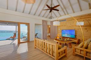 a living room with a couch and a tv and a table at You & Me Maldives - Adults Only - Premium All-Inclusive in Raa Atoll