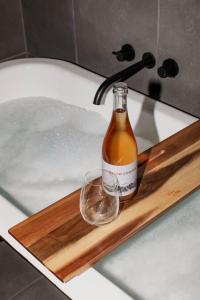a bottle of alcohol sitting on a wooden tray in a bath tub at Happy Nomad in St Helens