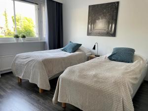 two beds in a room with a window at Kotimaailma Apartments near center apartment+sauna in Lahti