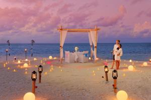 a man and a woman standing on the beach with a wedding on the beach at You & Me Maldives in Raa Atoll