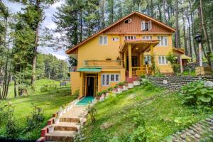 a yellow house on a hill in the woods at Hotel Little Silver in Pahalgām