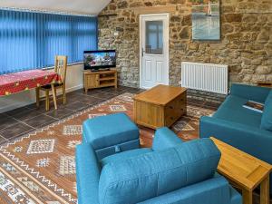a living room with a blue couch and a tv at Church Cottage in Two Dales
