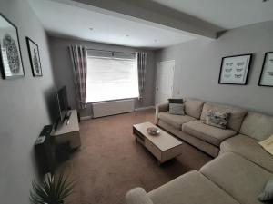 a living room with a couch and a table at Pear Tree House in Beeston