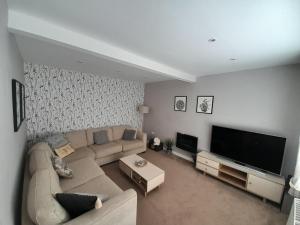 a living room with a couch and a flat screen tv at Pear Tree House in Beeston