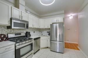 a kitchen with white cabinets and a stainless steel refrigerator at Chicago Condo Laptop Workspace, 6 Mi to Downtown! in Chicago