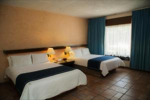 a hotel room with two beds and a window at Mision De Los Angeles in Oaxaca City